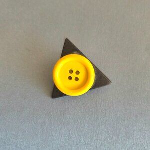 Vintage plastic brooch/pin with bright yellow button on black triangles.
